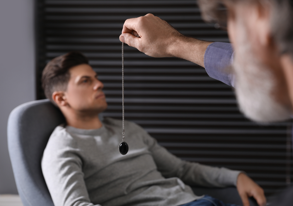 Psychotherapist using pendulum during hypnotherapy   session in office
